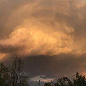 golden billowy clouds tiny rainbow after a storm